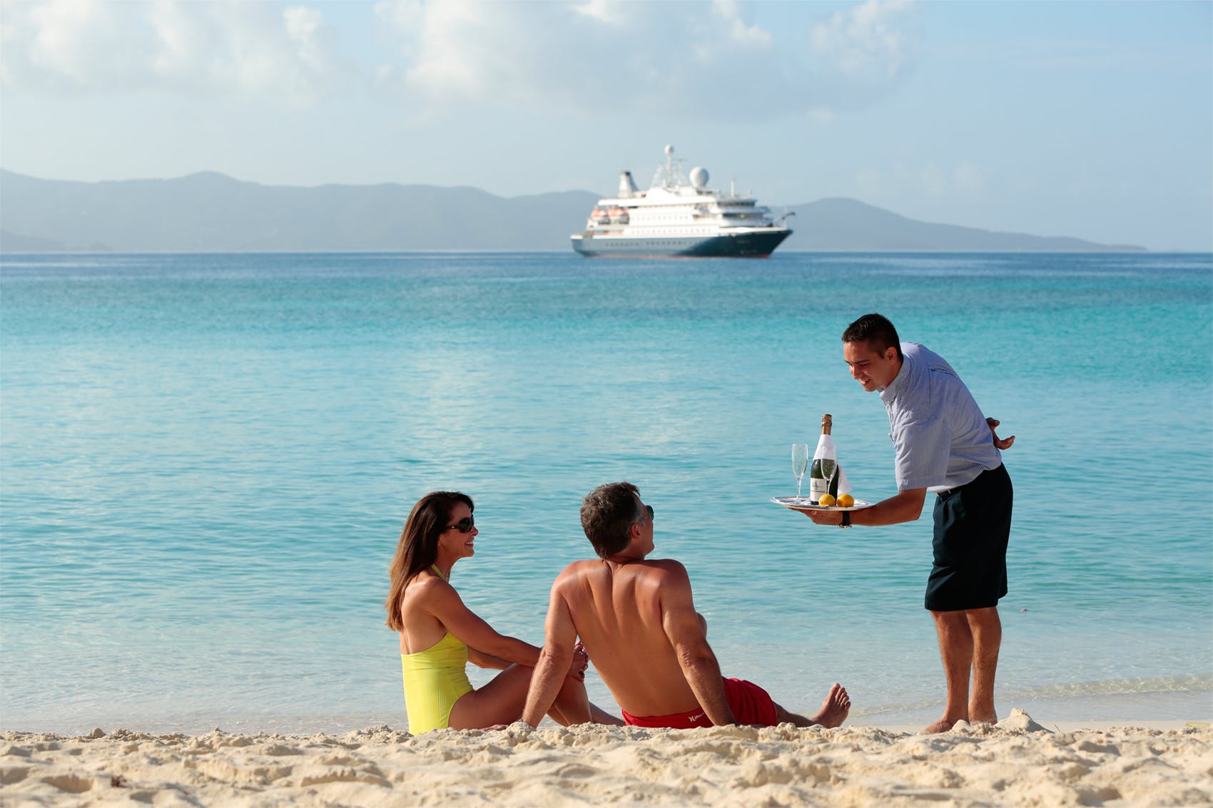 Couple being served drinks by SeaDream staff at the beach