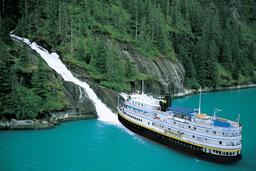 Uncruise ship - SS Legacy next to a waterfall.