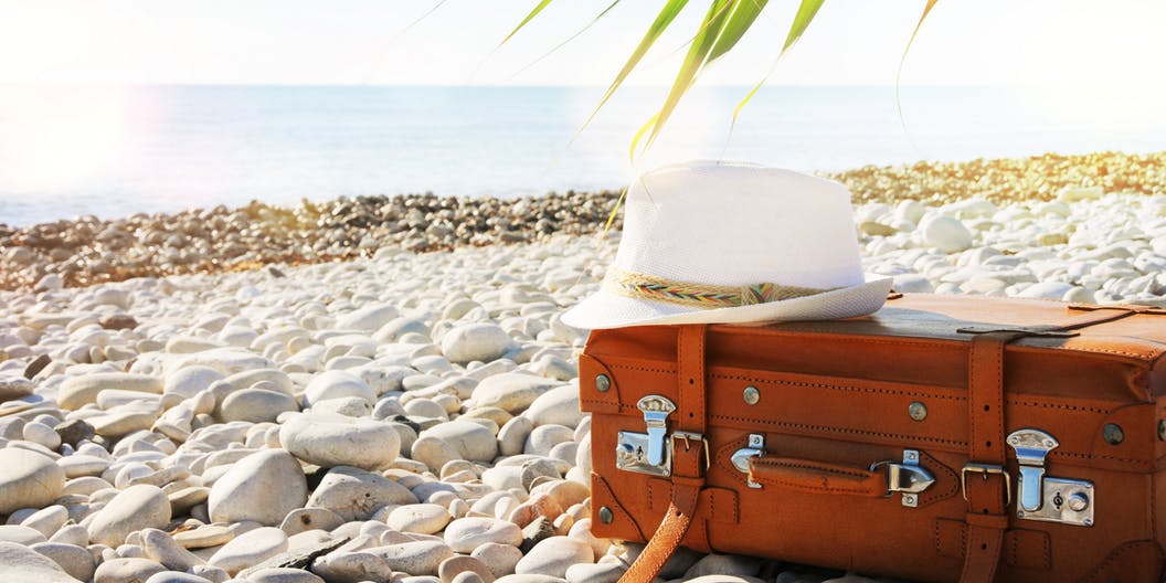 Suitcase and hat on the beach